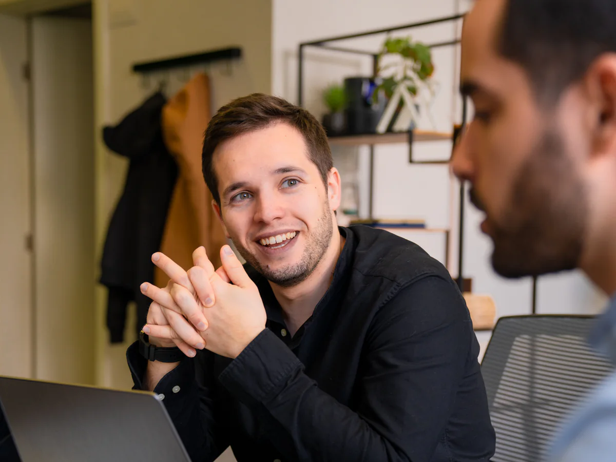 Two of the AppX team talking over a laptop across a meeting table