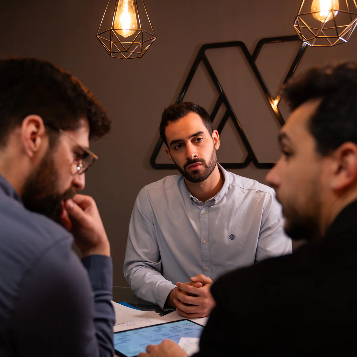 Three of the AppX team in conversation across a meeting table